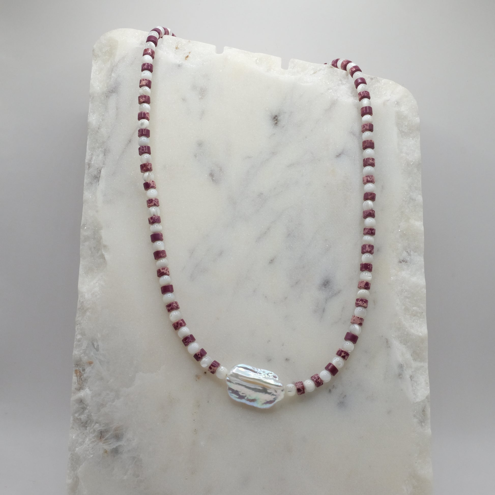 Necklace with red and white beads on a marble surface