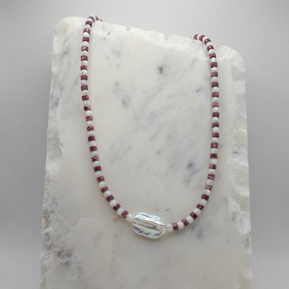 Necklace with red and white beads on a marble surface