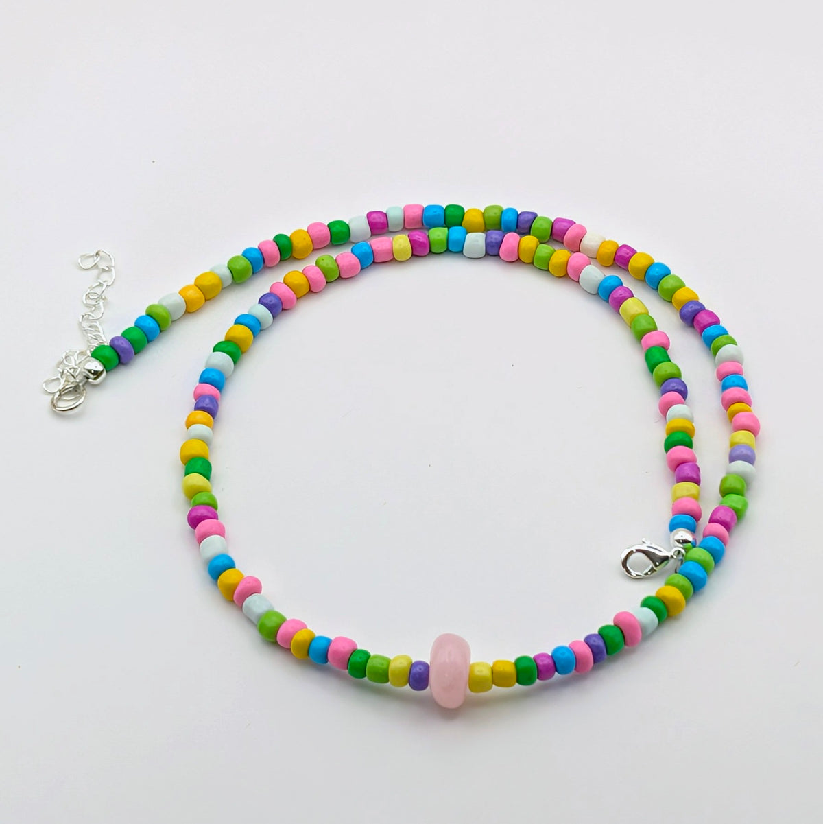 Colourful Rachel beaded necklace featuring rainbow glass beads, a dyed pale pink jade feature bead and silver clasp and extension chain.