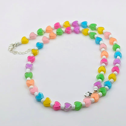 Colourful handmade beaded necklace featuring rainbow translucent heart beads, white glass seed beads and silver-plated findings with an extension chain.