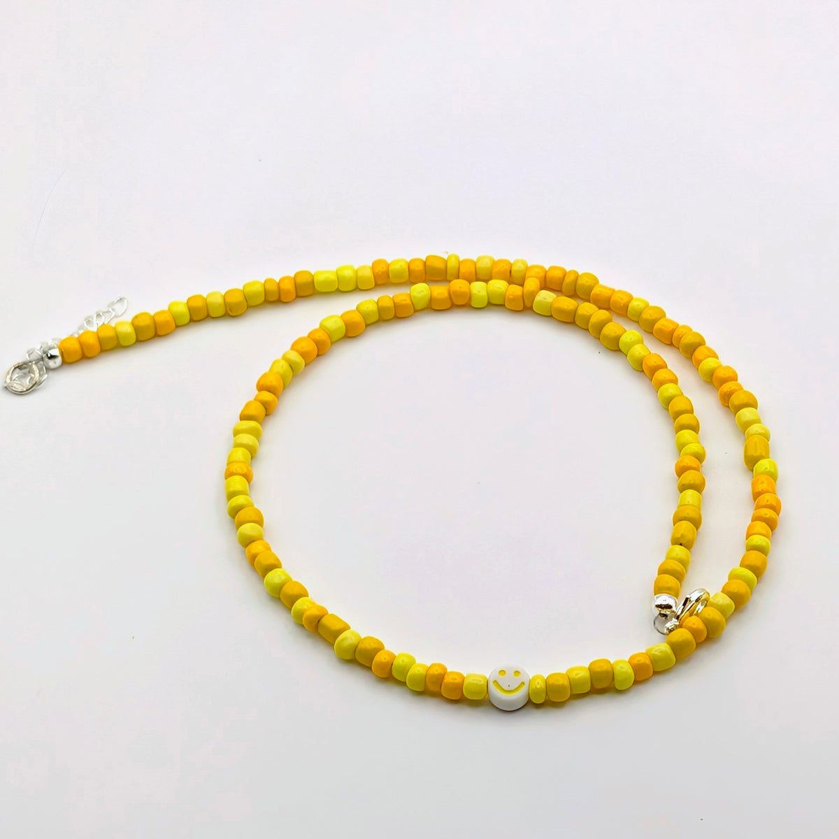 Yellow and orange Phoebe handmade beaded necklace with glass beads and a yellow smiley feature bead.