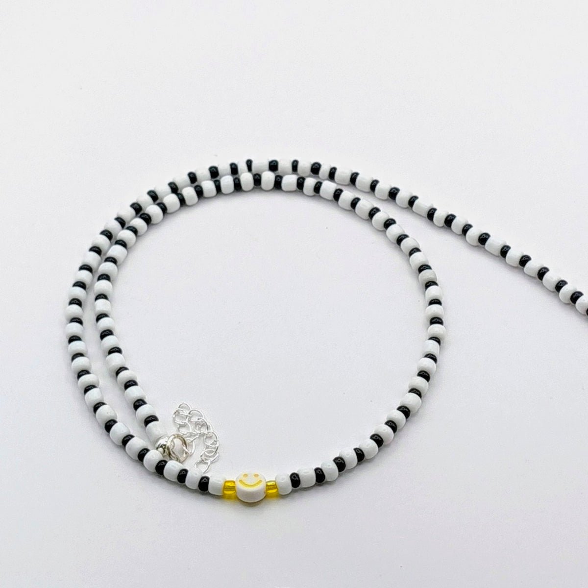 Black and white Phoebe handmade beaded necklace with glass beads and a yellow smiley bead, quirky statement jewellery.