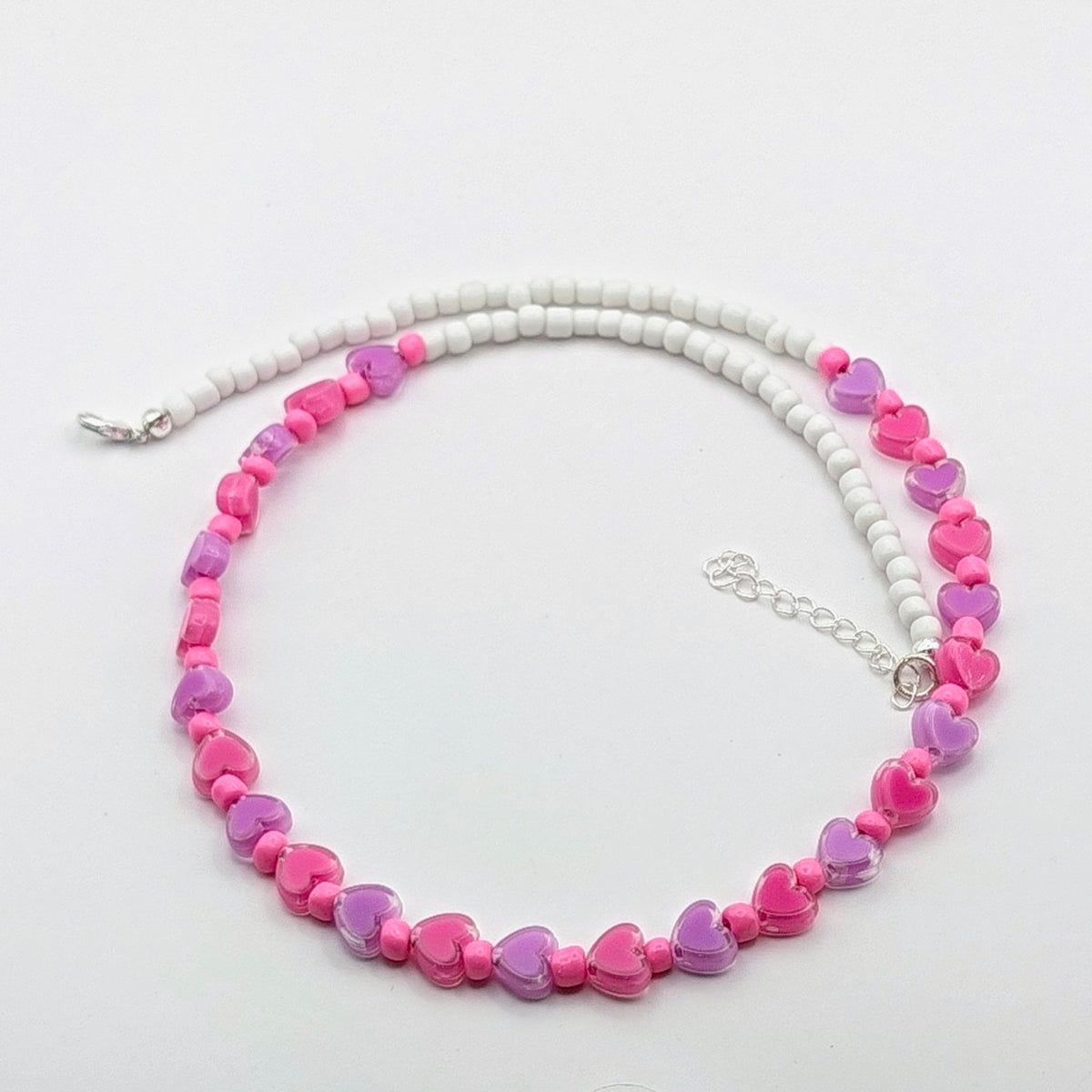 Ursula handmade beaded necklace with white glass beads, pink and purple translucent heart beads, bright pink accents and silver adjustable hardware.
