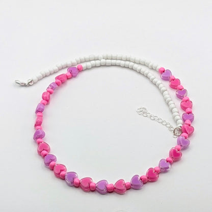 Ursula handmade beaded necklace with white glass beads, pink and purple translucent heart beads, bright pink accents and silver adjustable hardware.