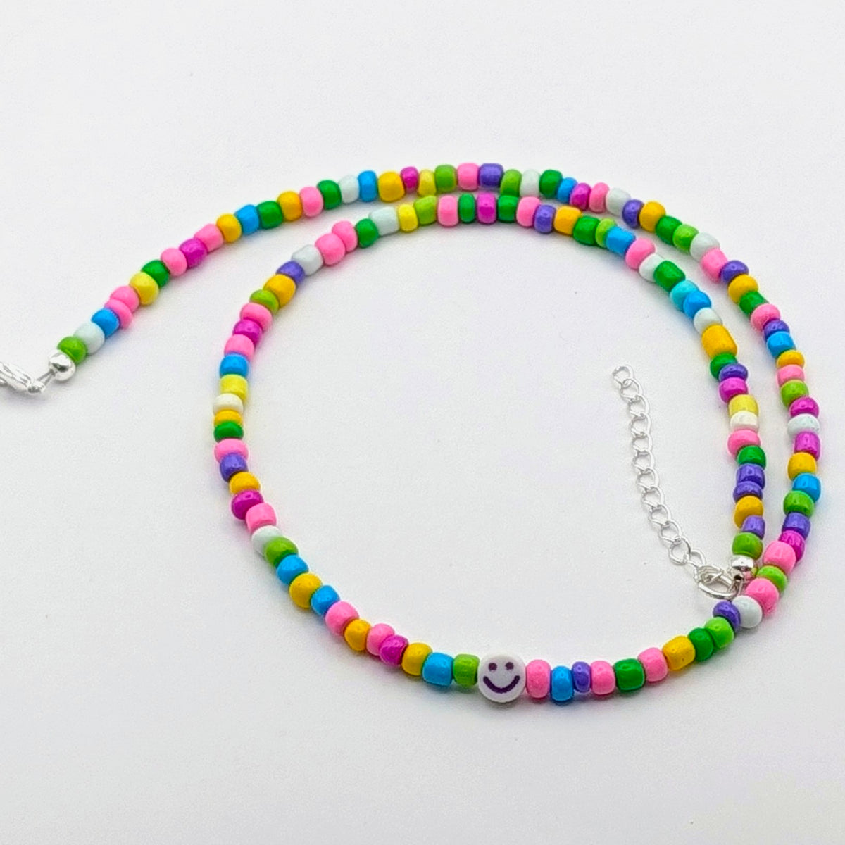 Rainbow Phoebe handmade beaded necklace with colourful glass beads and a purple smiley bead, dopamine jewellery.