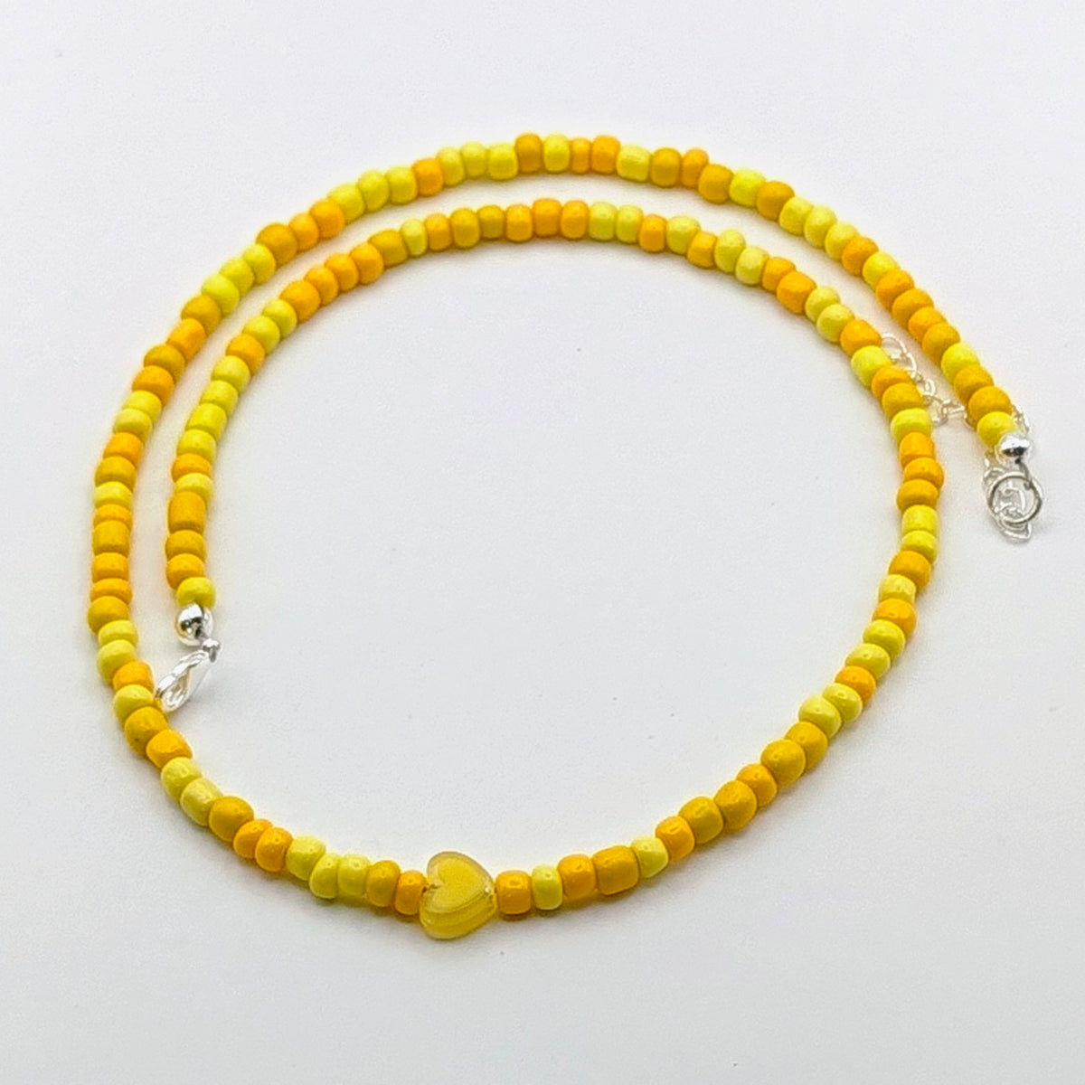 Sara colourful beaded necklace with yellow and golden glass beads, translucent yellow heart bead and silver adjustable hardware.
