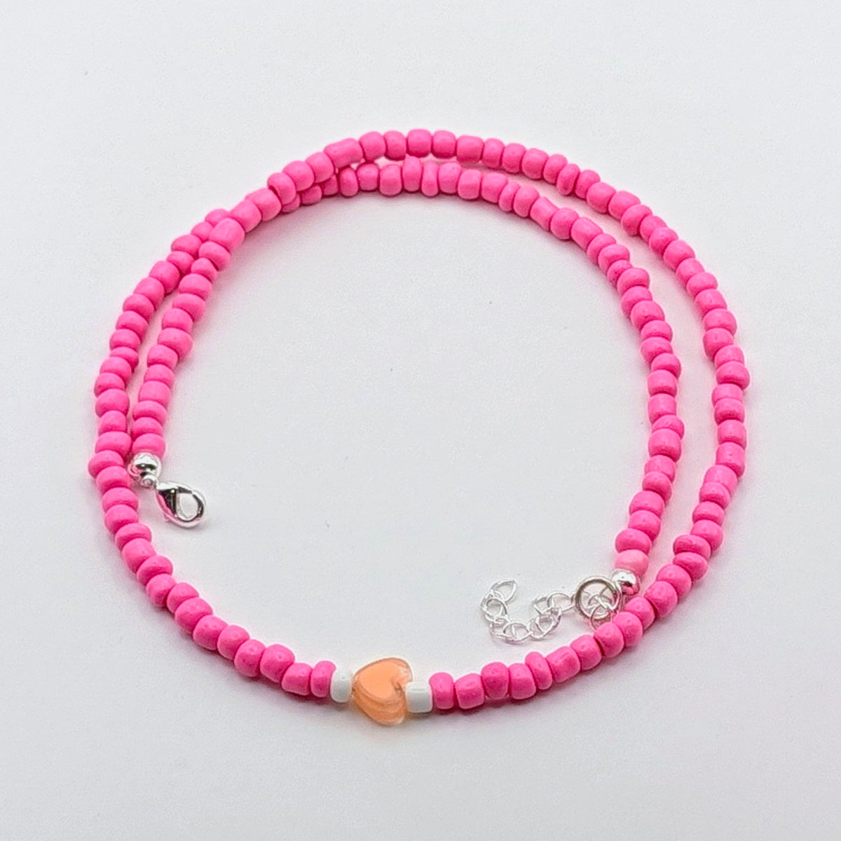 Sara handmade pink beaded necklace featuring bright pink glass beads, peach heart bead, white accents and silver hardware.