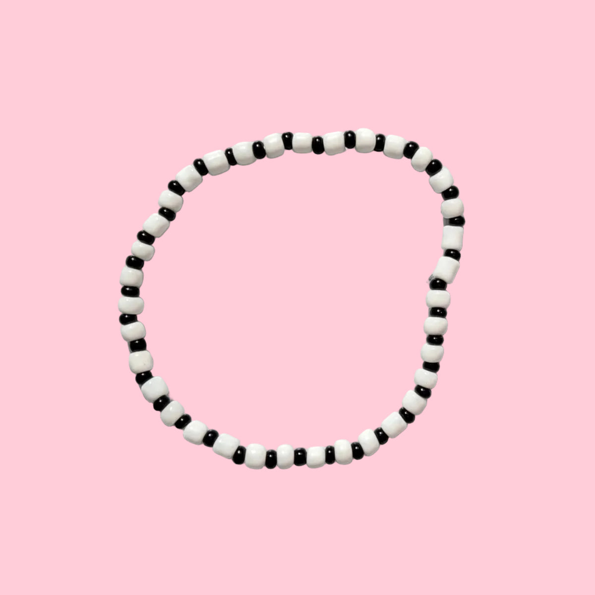 A circular black and white beaded necklace or bracelet displayed against a textured white wall.
