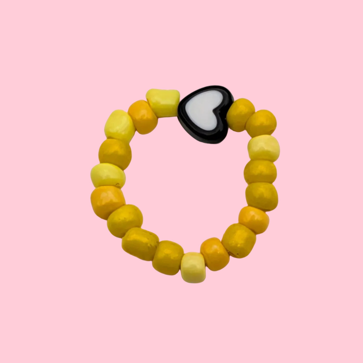 A beaded stretch ring composed of yellow and yellow-orange round beads, featuring a central black heart-shaped charm with a white center, displayed on a plain off-white background.