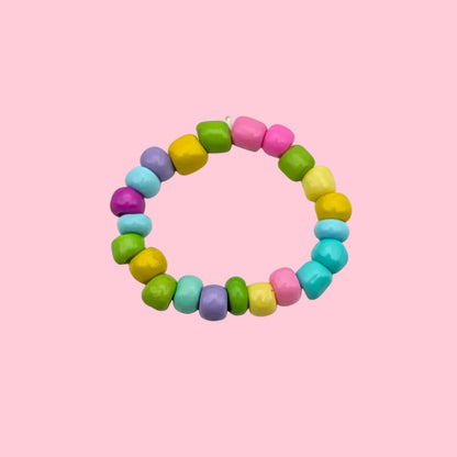 A beaded stretch ring made of small, rounded pastel-colored beads in pink, yellow, green, blue, and purple, arranged in a circle on a plain white background.
