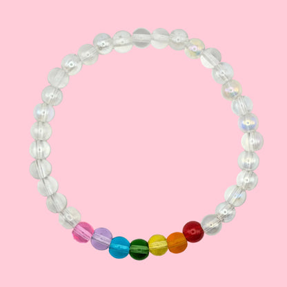 Maisie handmade bracelet by Velveteen Sunshine, featuring clear 6mm glass beads with a small rainbow section on a pink background.