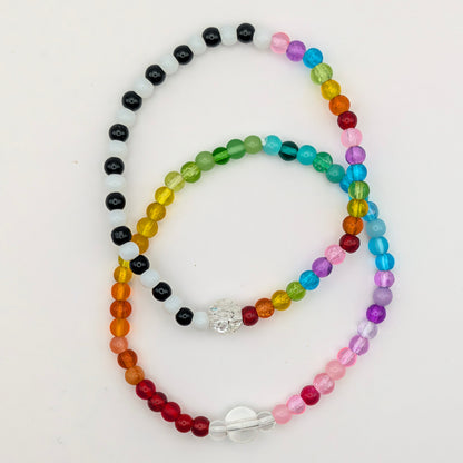 Two handmade Lola glass bead bracelets by Velveteen Sunshine: full rainbow Jellybean and black, white and rainbow Joyride, overlapping.