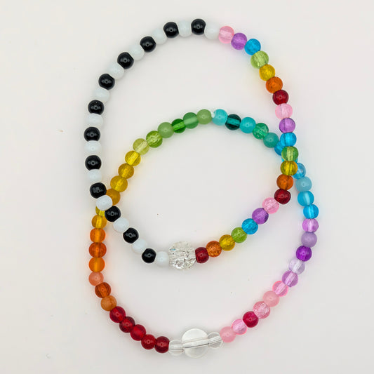 Two handmade Lola glass bead bracelets by Velveteen Sunshine: full rainbow Jellybean and black, white and rainbow Joyride, overlapping.