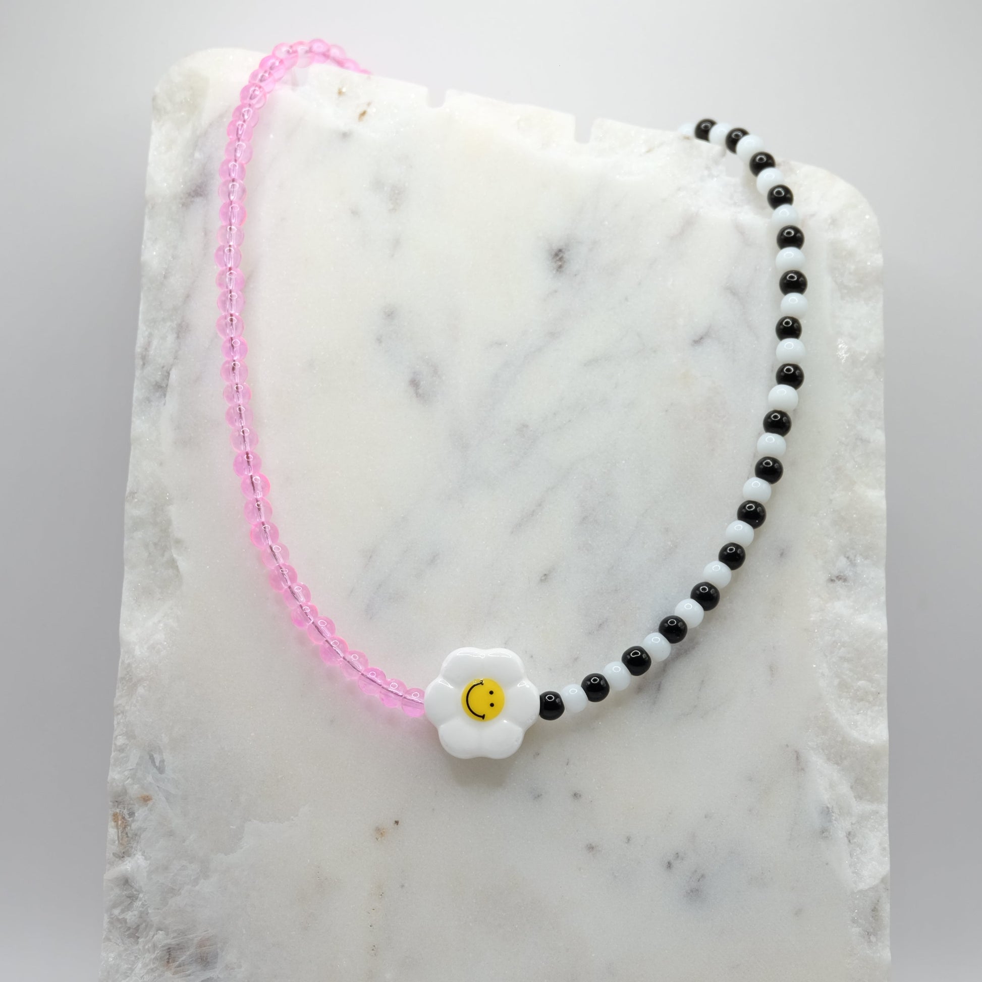 Necklace with a ceramic flower-shaped bead on a marble surface