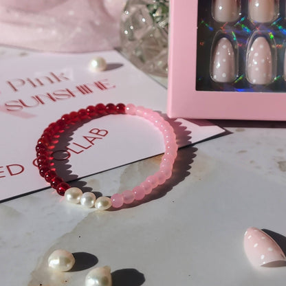 Pink hairband with pearls, nail display box, and red flowers on a light surface.