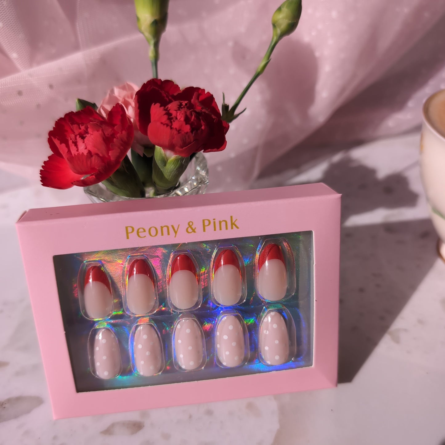 Pink nail polish set with flowers in a glass vase on a textured surface