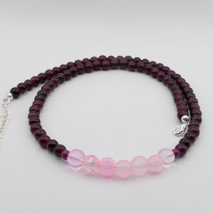 A handmade beaded necklace composed of 6mm deep plum glass beads, featuring a central cluster of soft pink 8mm glass beads accented by small plum beads, shown on a white background.