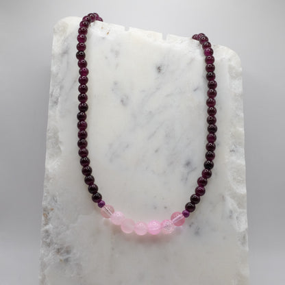 Necklace with purple and pink beads on a marble surface