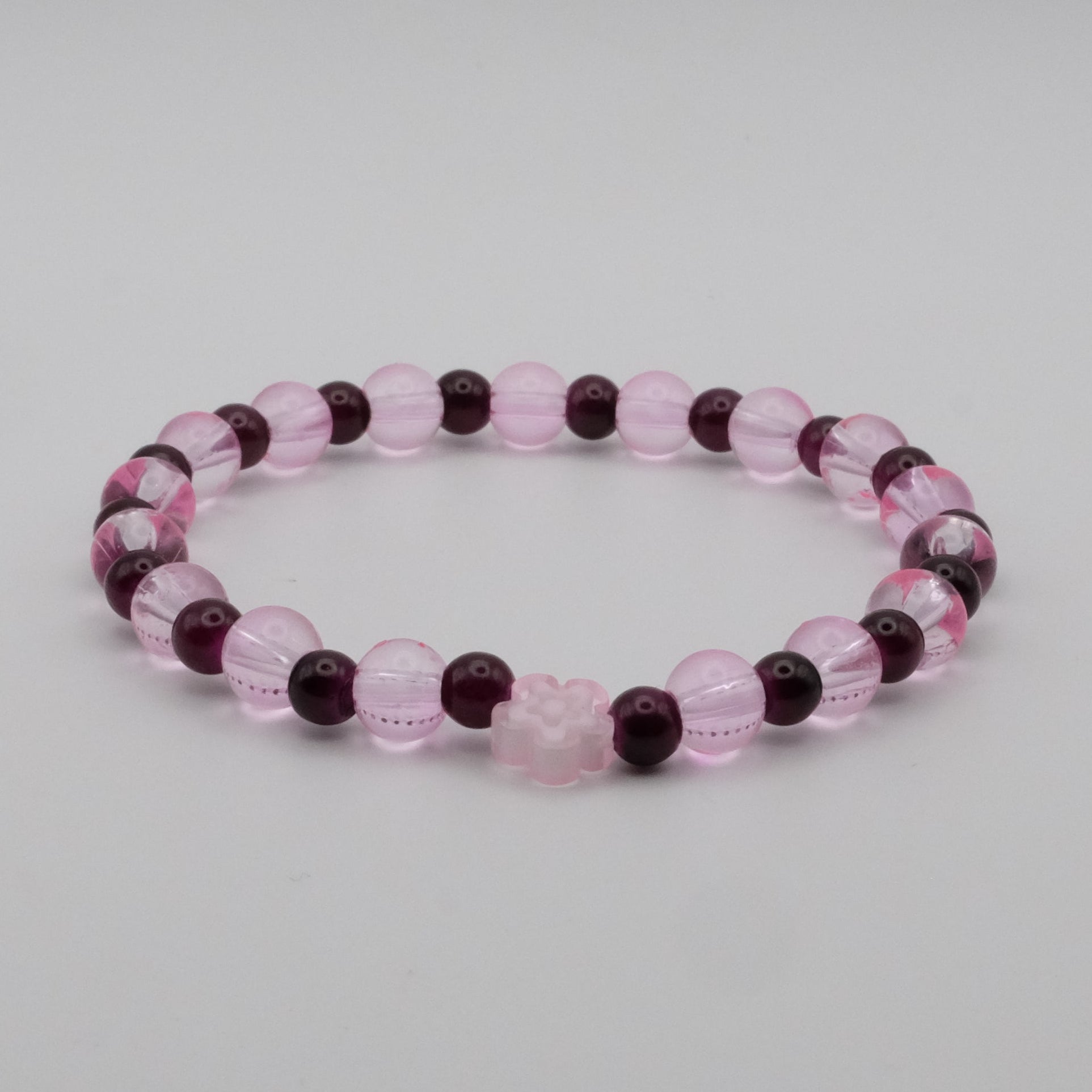 Beaded bracelet with pink and purple beads on a light gray background