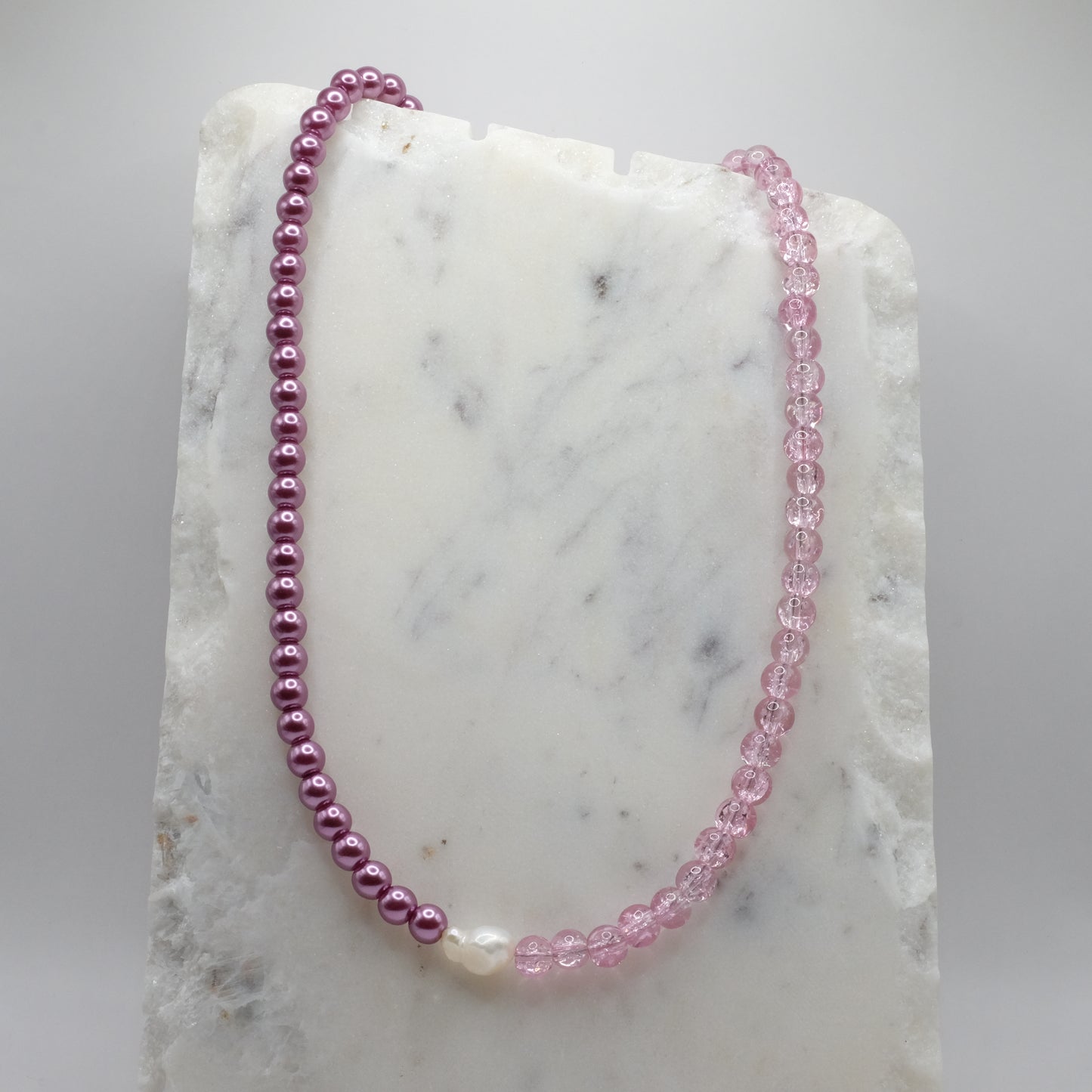 Pink beaded necklace on a marble surface