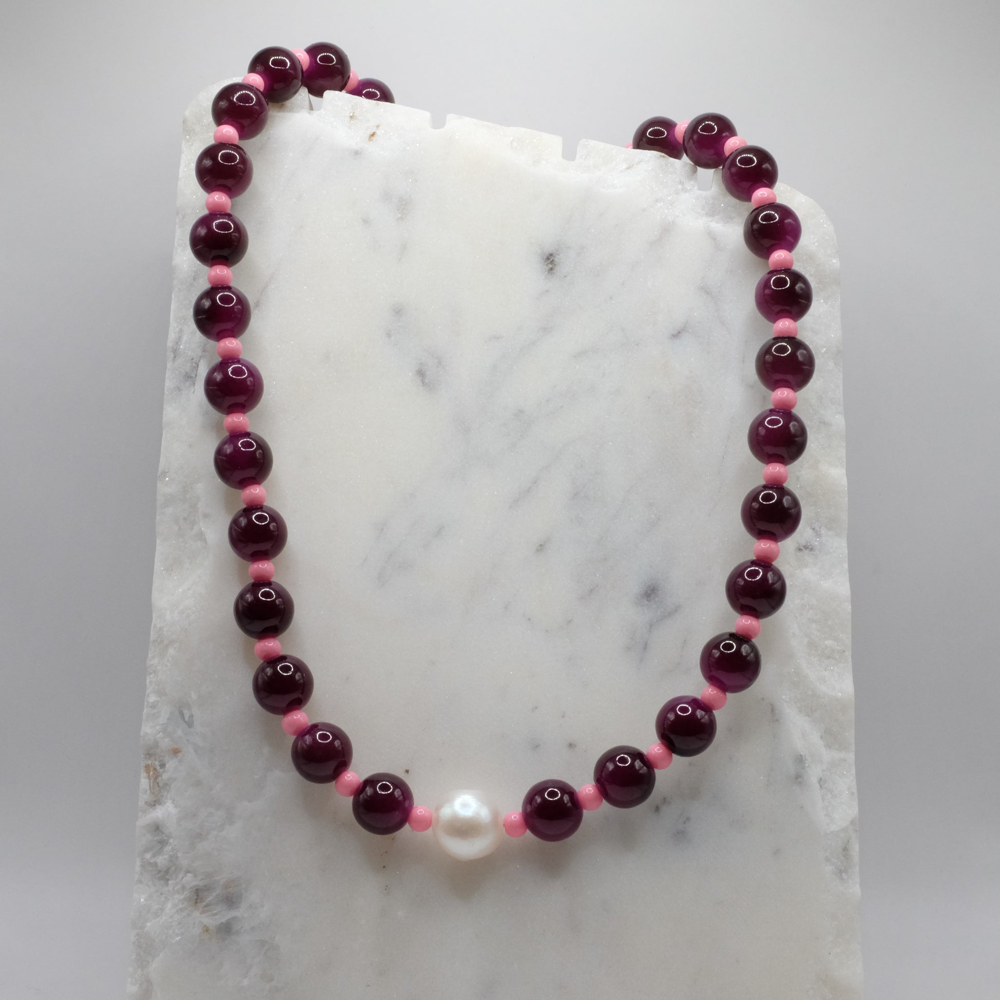 Beaded necklace with purple and pink beads on a marble surface