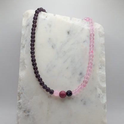 Two beaded bracelets, one purple and one pink, on a marble surface.