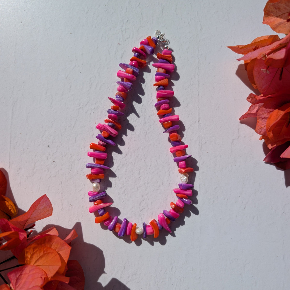 Colourful handmade necklace with irregular pink, orange and purple shell chip beads and scattered freshwater pearls.