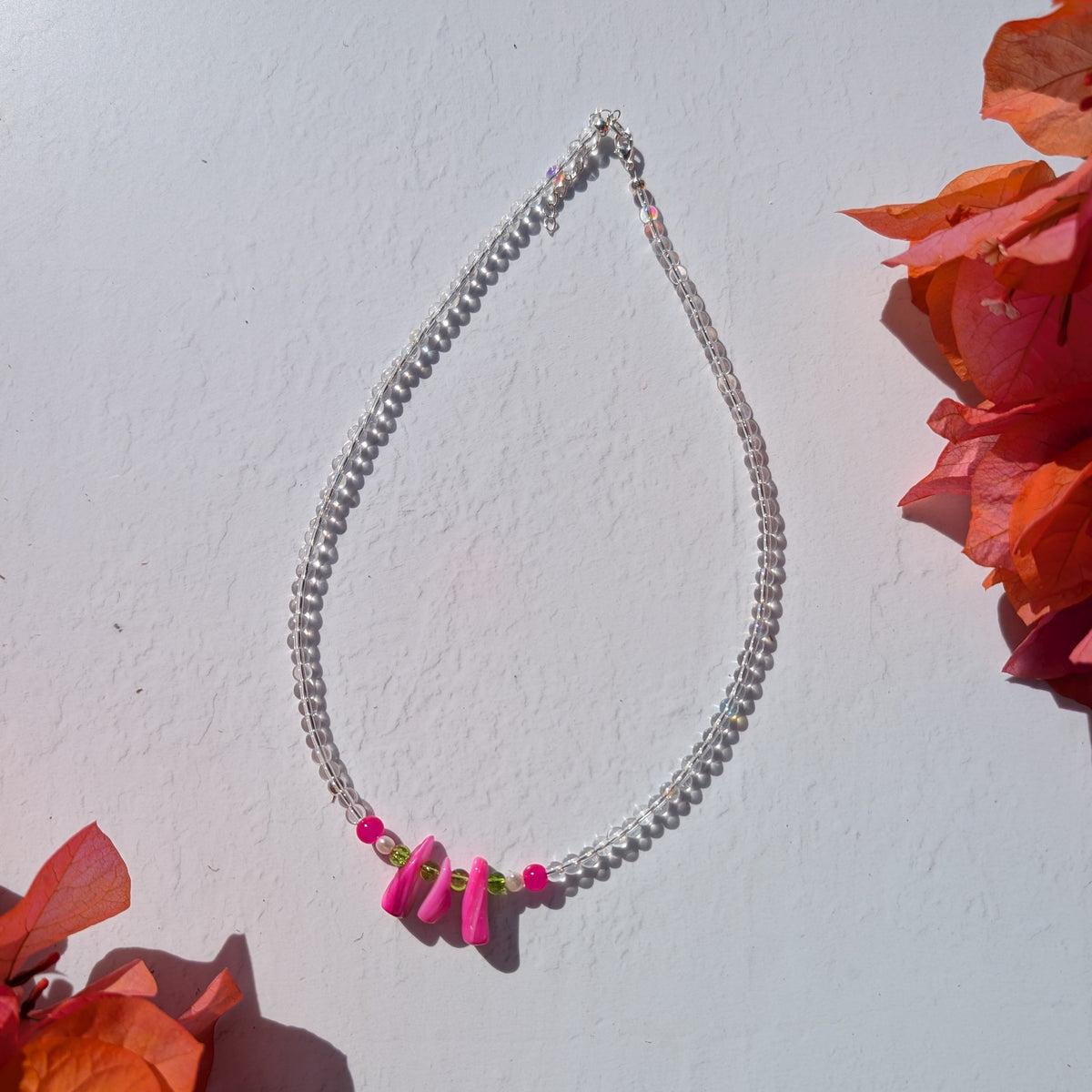 Handmade clear glass beaded necklace with pink and green glass accents and three bright pink shell chip beads at the centre.