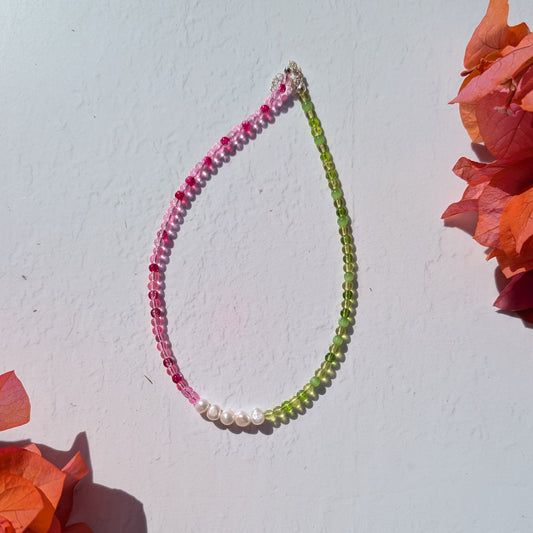 Handmade beaded necklace with pink and green glass beads and a row of freshwater pearls at the centre.