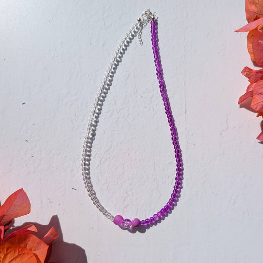 Handmade beaded necklace with clear and purple glass beads and three purple glass beads forming a simple centre detail.