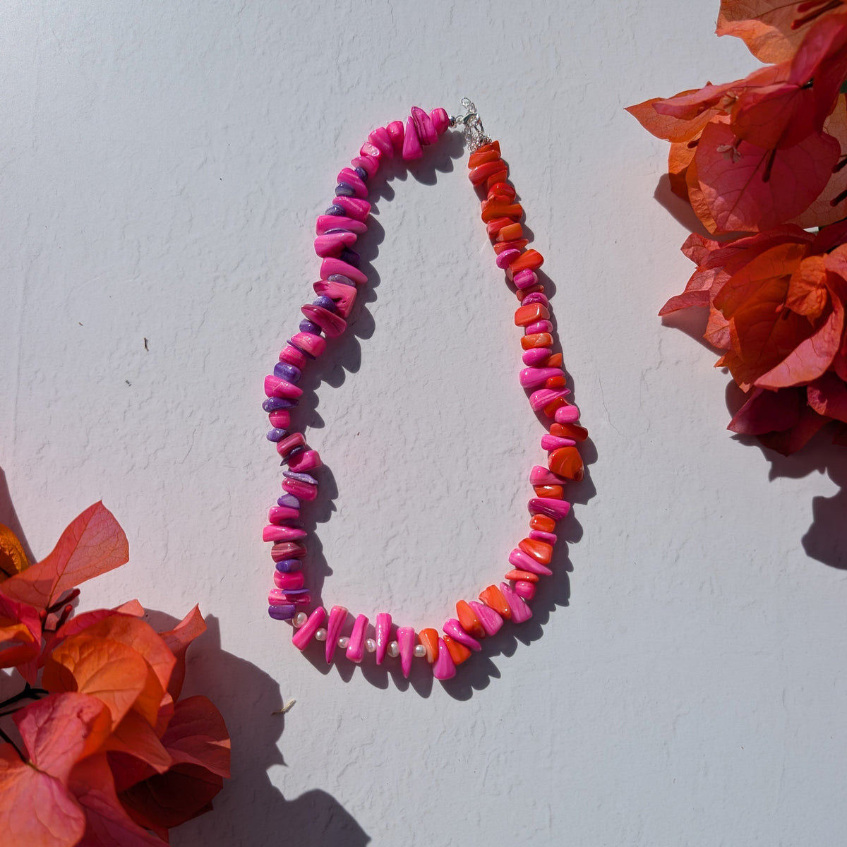 Colourful handmade necklace with pink, purple and orange shell chip beads and delicate freshwater pearl details.