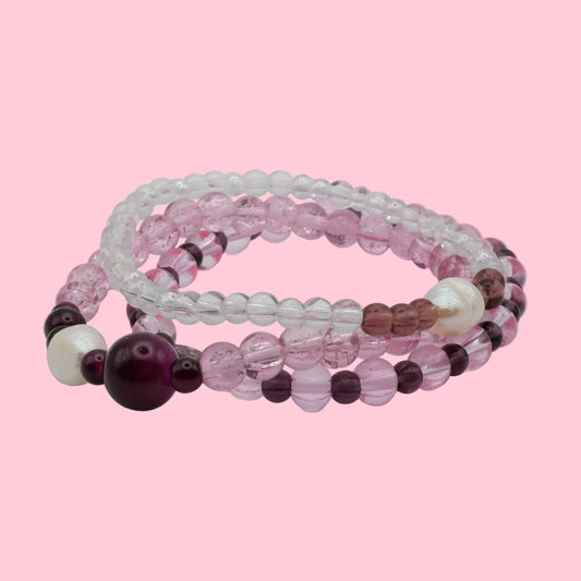Layered bracelet stack featuring blush pink glass beads, freshwater pearls, crystal beads and soft plum accents.
