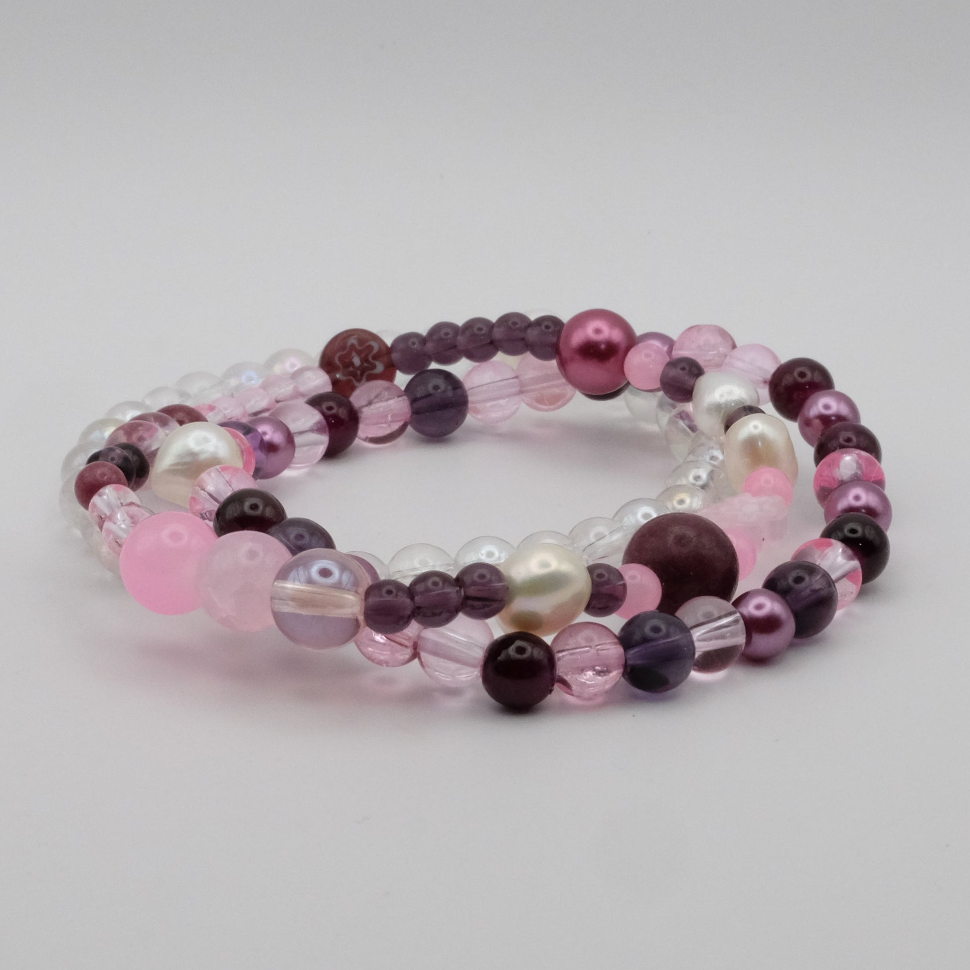 Beaded bracelet with pink, purple, and white beads on a light gray background