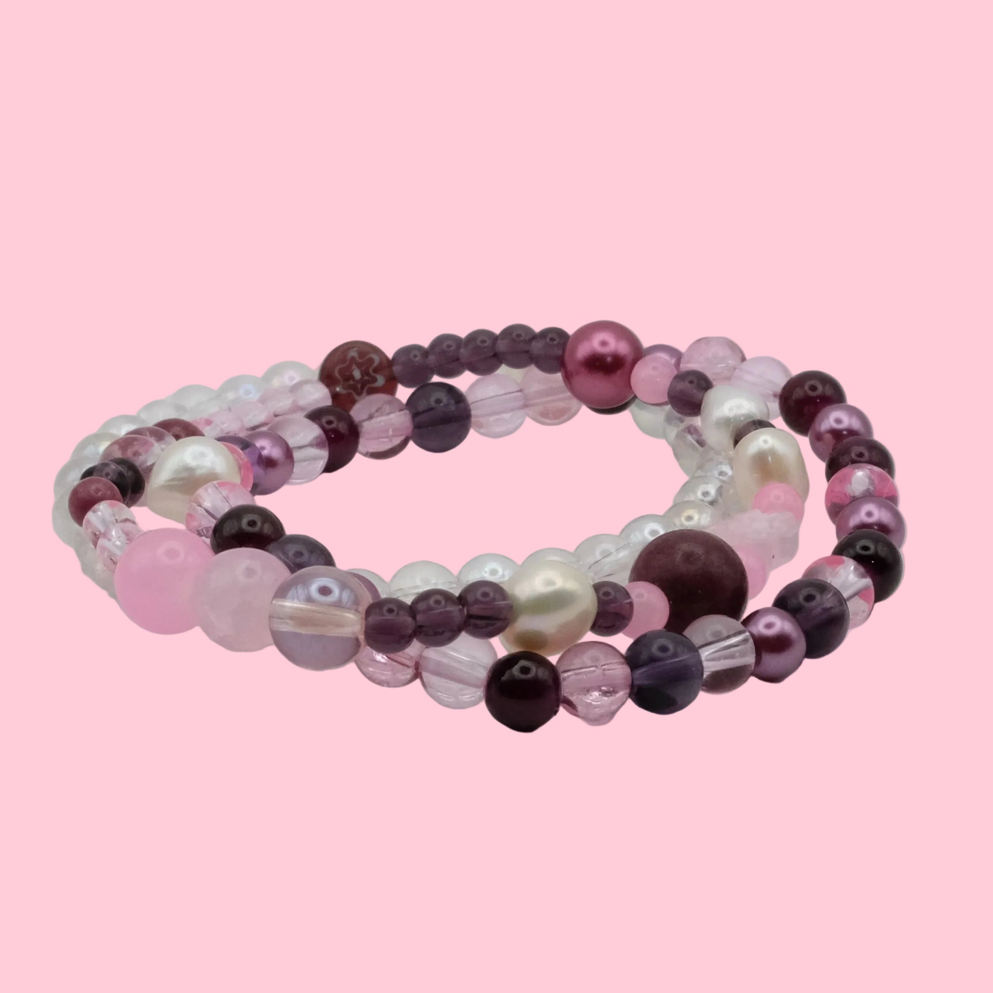 Layered handmade bracelet stack featuring pink and plum glass beads, freshwater pearls, pearl-look beads and crystal accents.