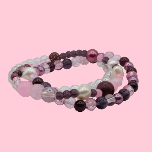 Layered handmade bracelet stack featuring pink and plum glass beads, freshwater pearls, pearl-look beads and crystal accents.