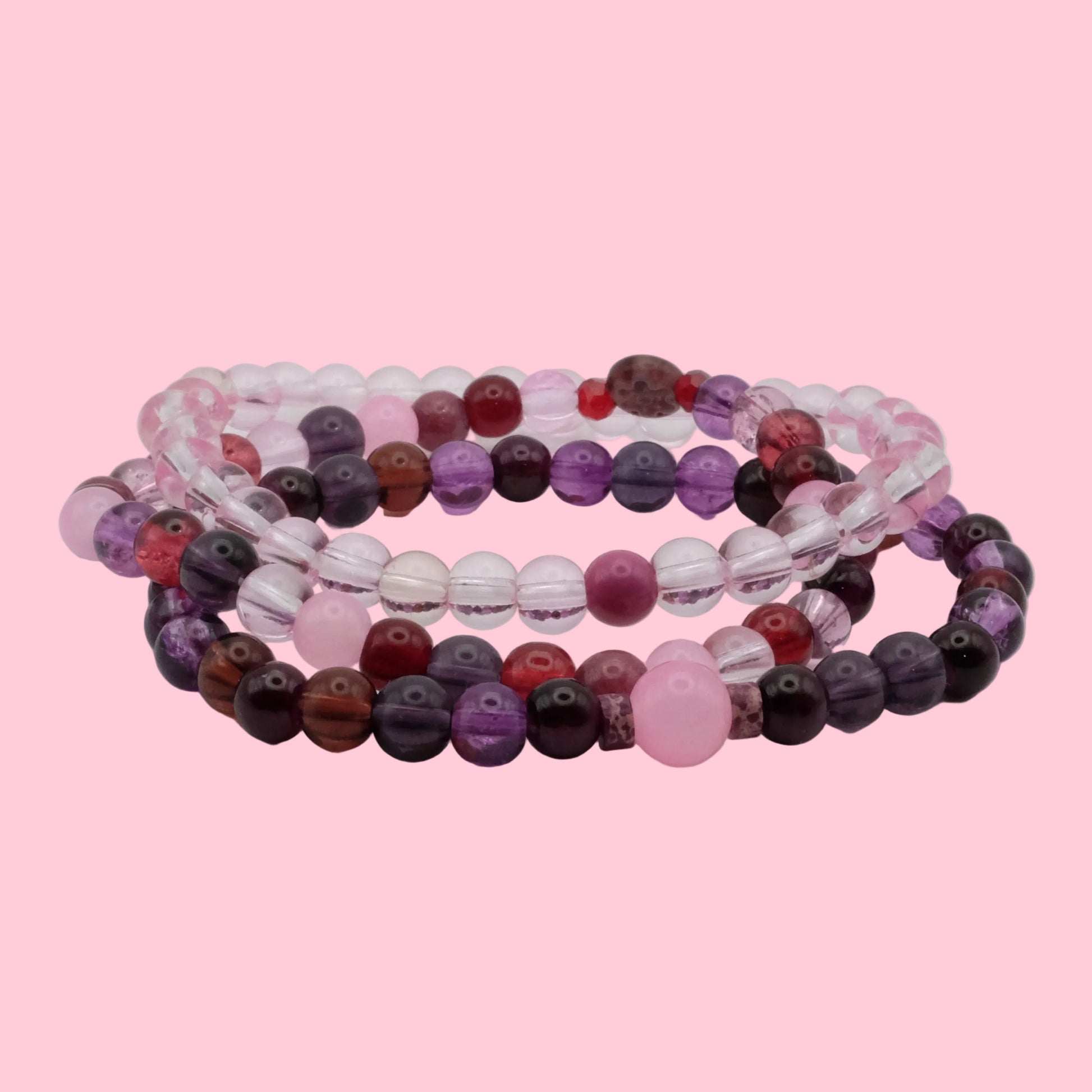 Handmade bracelet stack featuring violet glass beads, blush pink accents, crystal beads and soft berry tones.