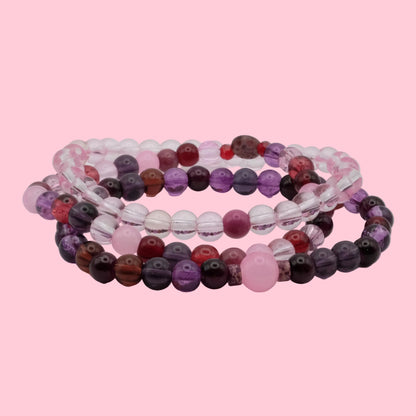 Handmade bracelet stack featuring violet glass beads, blush pink accents, crystal beads and soft berry tones.
