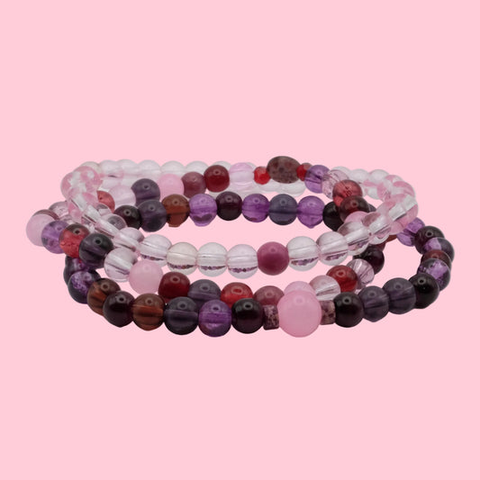 Handmade bracelet stack featuring violet glass beads, blush pink accents, crystal beads and soft berry tones.