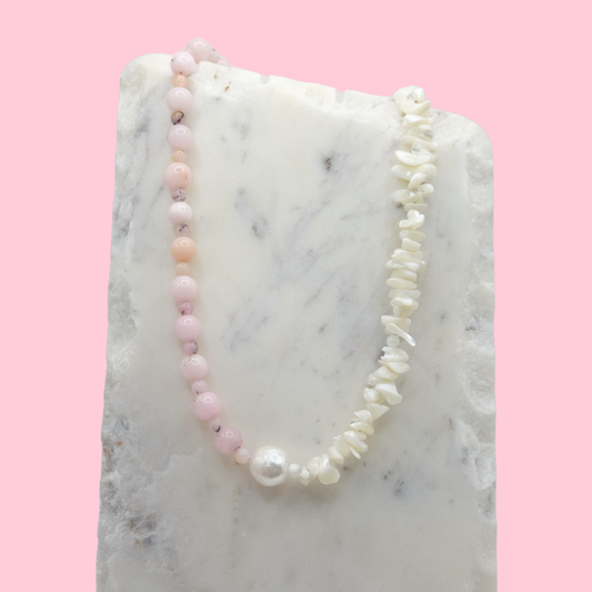 Necklace with pink and white beads on a marble surface with a pink background